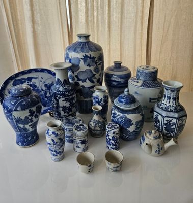 many blue and white vases and cups on the table
