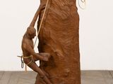 une sculpture en bois représentant un homme assis sur un rocher