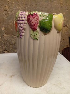 a white vase with fruit on it sitting on a table