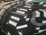 a black car parked in a parking lot next to other cars