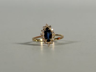 a close up of a blue sapphire and diamond ring on a white surface