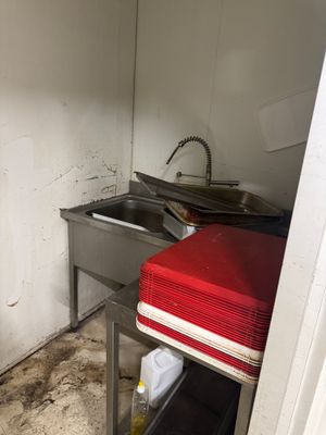 une cuisine sale avec un évier et une cuisinière