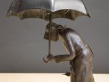 a statue of a person holding an umbrella on a table