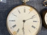 two old pocket watches sitting next to each other on a blue cloth