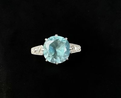 a close up of a ring with a blue topaz stone and diamonds