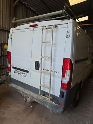 une camionnette blanche garée dans un garage, avec une échelle à l'arrière