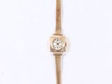 a gold watch with a diamond on the face