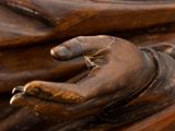 close up of a statue of a person with their hands on a piece of wood