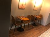 tables and chairs in a room with a wooden floor and a wall