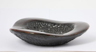 a black bowl sitting on top of a table next to an open book