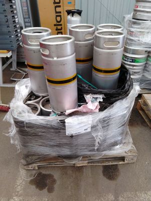 Plusieurs fûts de bière sont empilés sur une palette dans un entrepôt