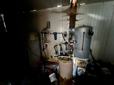 une photo d'une pièce où se trouvent un chauffe-eau et de nombreux outils