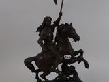 bronze statue of a man on a horse holding a flag