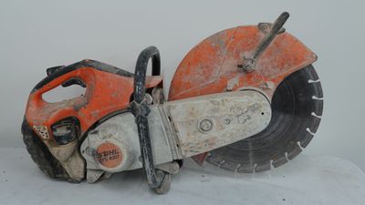 une tronçonneuse orange et noire posée sur une surface blanche