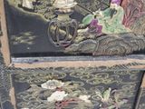 a black chest of drawers with a painting on it