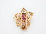 a close up of a gold brooch with a pink stone