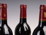 three bottles of red wine are lined up on a table