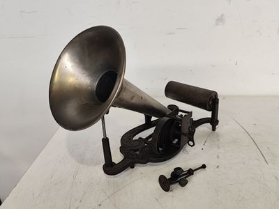 un vieux gramophone argenté et noir posé sur une table blanche