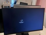 a computer monitor sitting on a desk with a charger