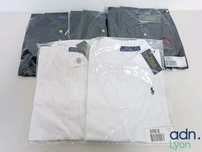 three shirts that are wrapped in plastic on a table