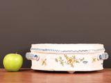 a green apple sitting next to a white bowl on a table