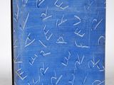 un vieux livre bleu, sur lequel on voit des inscriptions, posé sur une surface blanche