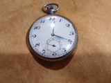 a silver pocket watch sitting on a brown surface