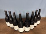 six bottles of wine lined up in a row on top of a wooden table