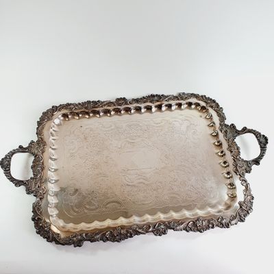 an ornate silver tray with handles and handles on a white surface
