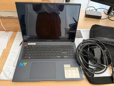 un ordinateur portable posé sur un bureau, à côté d'un chargeur