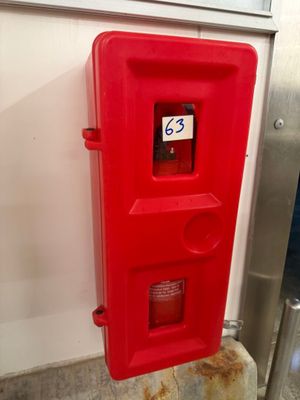 une borne d'incendie rouge adossée à un mur