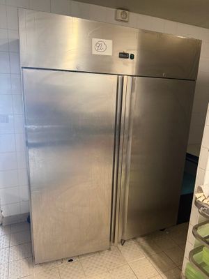 a stainless steel refrigerator in a kitchen with tiled flooring
