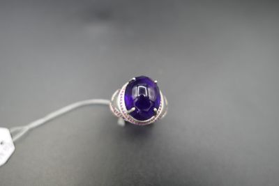 une image représentant une bague ornée d'une pierre violette sur un fond noir