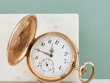 une montre de poche en or posée sur un bloc de marbre