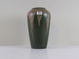 un vase vert posé sur une surface blanche