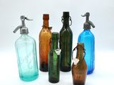 several different colored glass bottles are lined up on a white surface