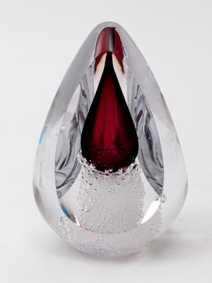 a red tear shaped glass object on a white surface