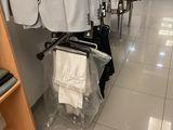 a lot of suits hanging on a rack in a store