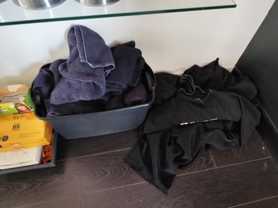 une valise noire sur laquelle est posée une serviette violette, à côté d'une pile de livres