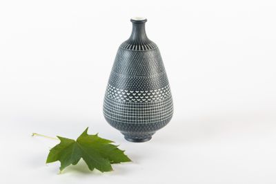 un vase noir avec une feuille verte à côté