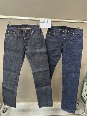 deux paires de jeans suspendues à un portant dans un magasin