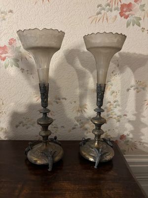 two glass vases sitting on a table in front of a floral wallpaper