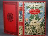 an old book with a red cover sitting on top of a table