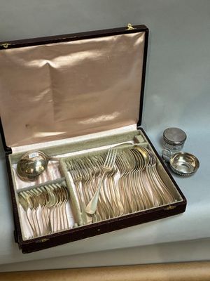 des couverts dans un coffret posé sur une table, à côté d'une cuillère et d'une fourchette