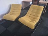 pair of yellow lounge chairs in an office setting with a desk and chair