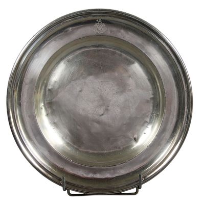 assiette en argent posée sur un support, sur fond blanc, avec un fond blanc