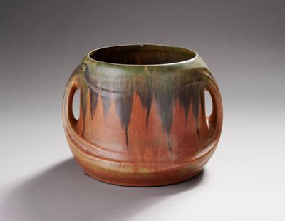 un vase marron et vert muni d'anses, sur un fond blanc