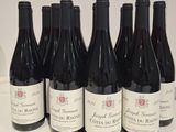 six bottles of red wine are lined up on a counter