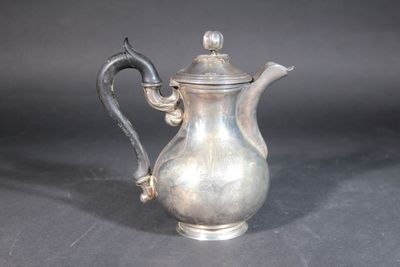 a silver tea pot with a handle on a table