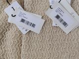 three tags on a sweater hang on a hanger in a store